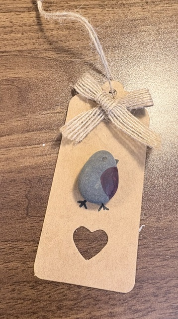 Finished handmade Christmas gift tag decorated with a painted pebble robin and hessian bow.